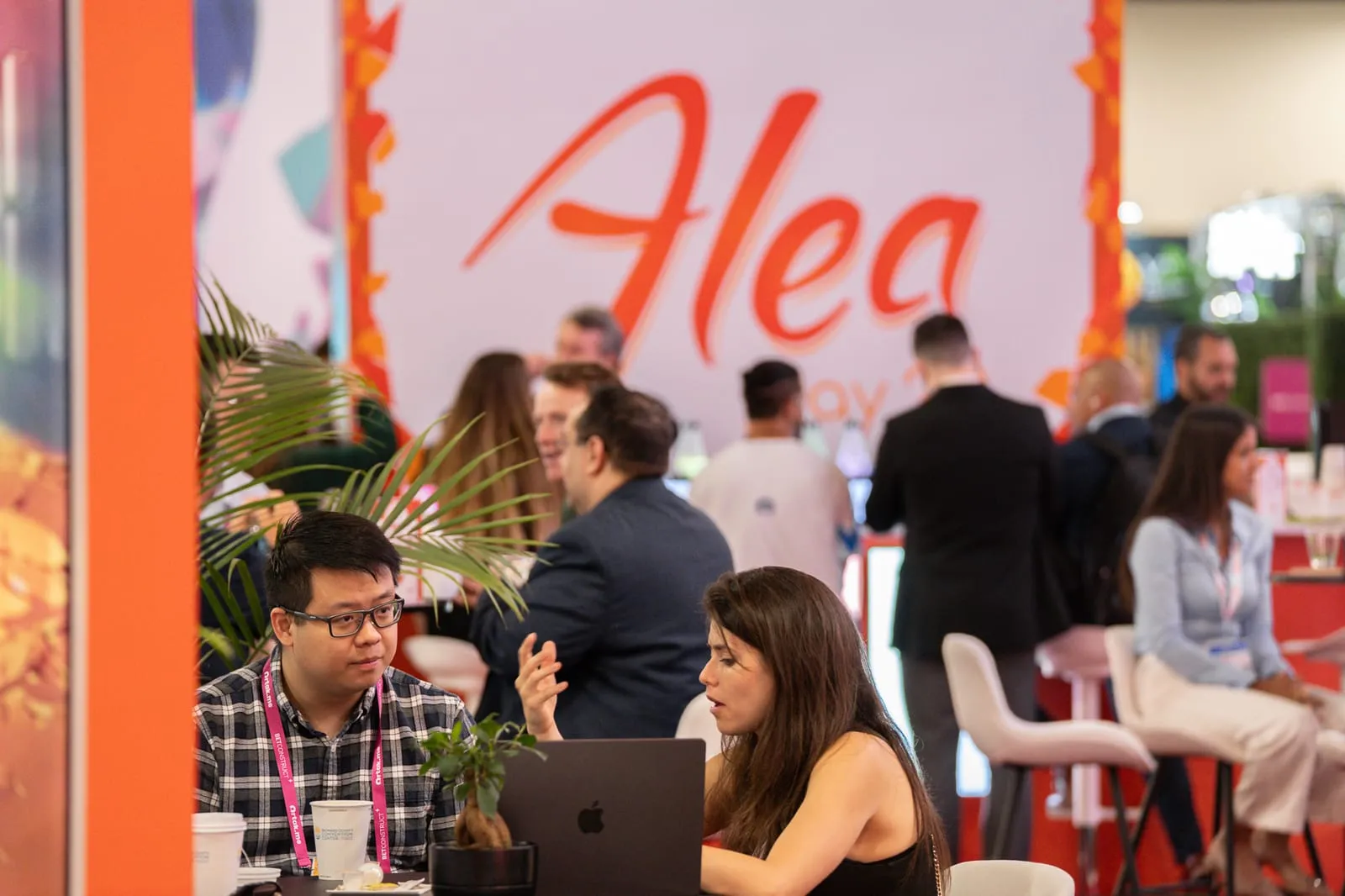 Attendees meeting over a laptop at the busy ALEA booth during SBC Summit Americas in Fort Lauderdale