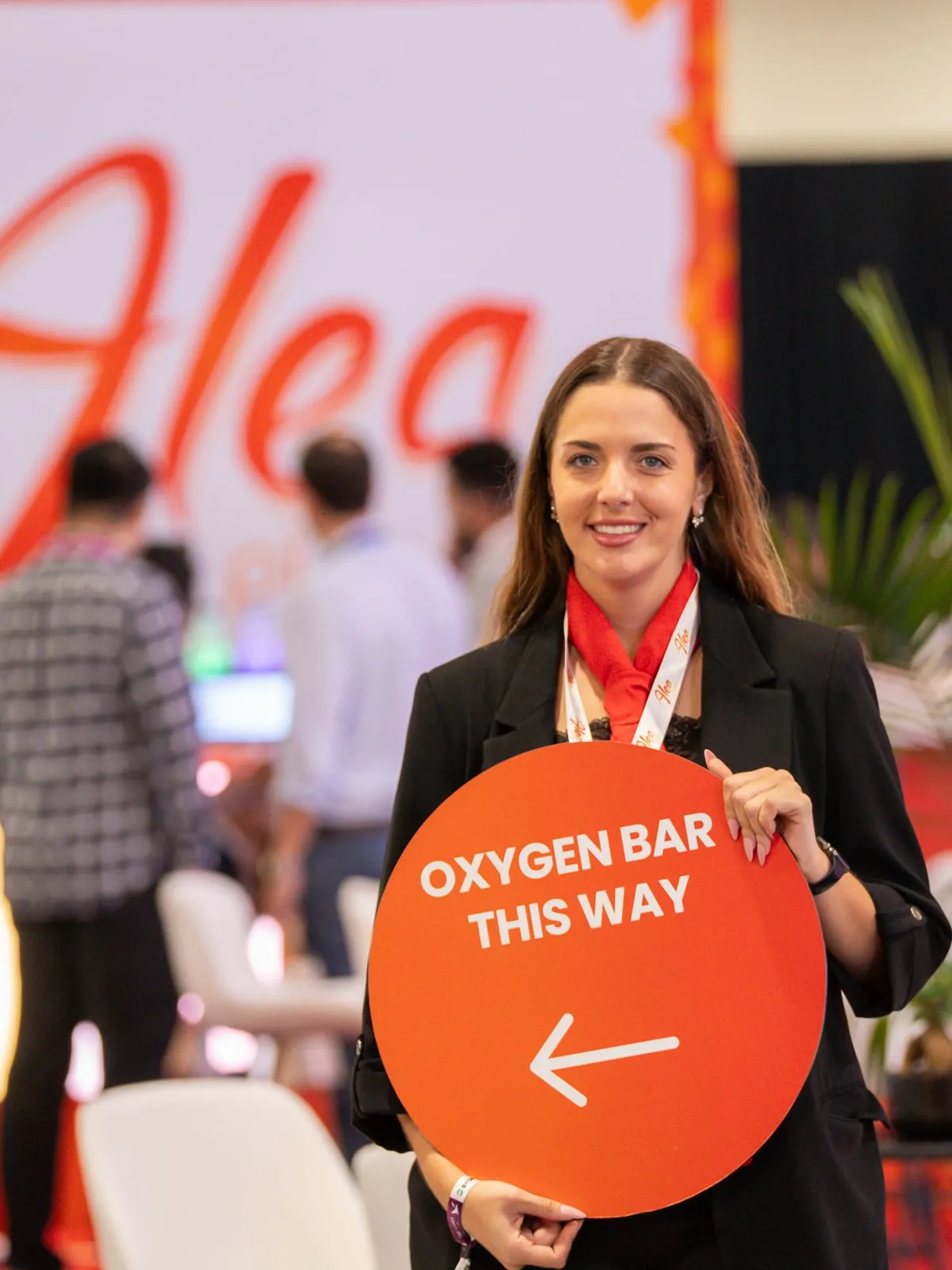 ALEA brand ambassador holding an Oxygen Bar sign at the ALEA booth, SBC Summit Americas in Fort Lauderdale