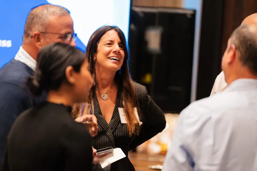 Guest in a pinstripe blazer laughs while networking at an American Express client dinner at Bourbon Steak