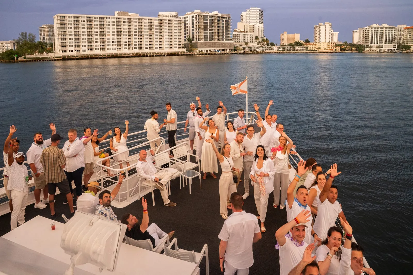 UVeye team in white waving from the bow of a yacht on the Fort Lauderdale Intracoastal at sunset