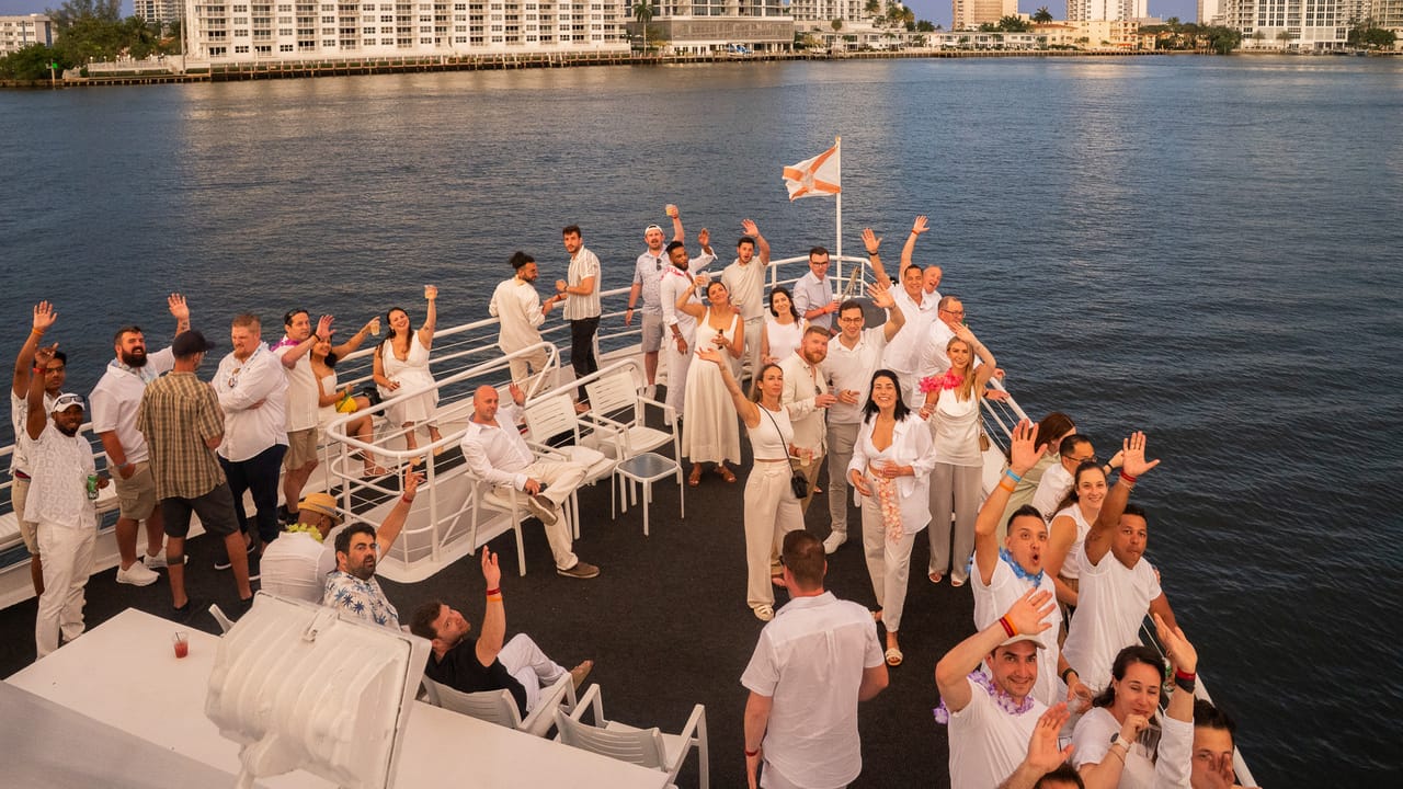 UVeye team in white waving from the bow of a yacht on the Fort Lauderdale Intracoastal at sunset, shot by Lunna Agency